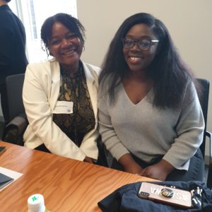 Technovation Girls Uber Job Shadow Day: Two young Black women are seated at a conference table, smiling