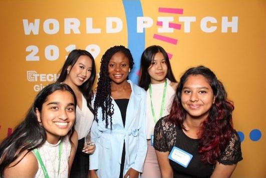 Student Ambassadors pose in front of a bright orange Technovation World Pitch Poster
