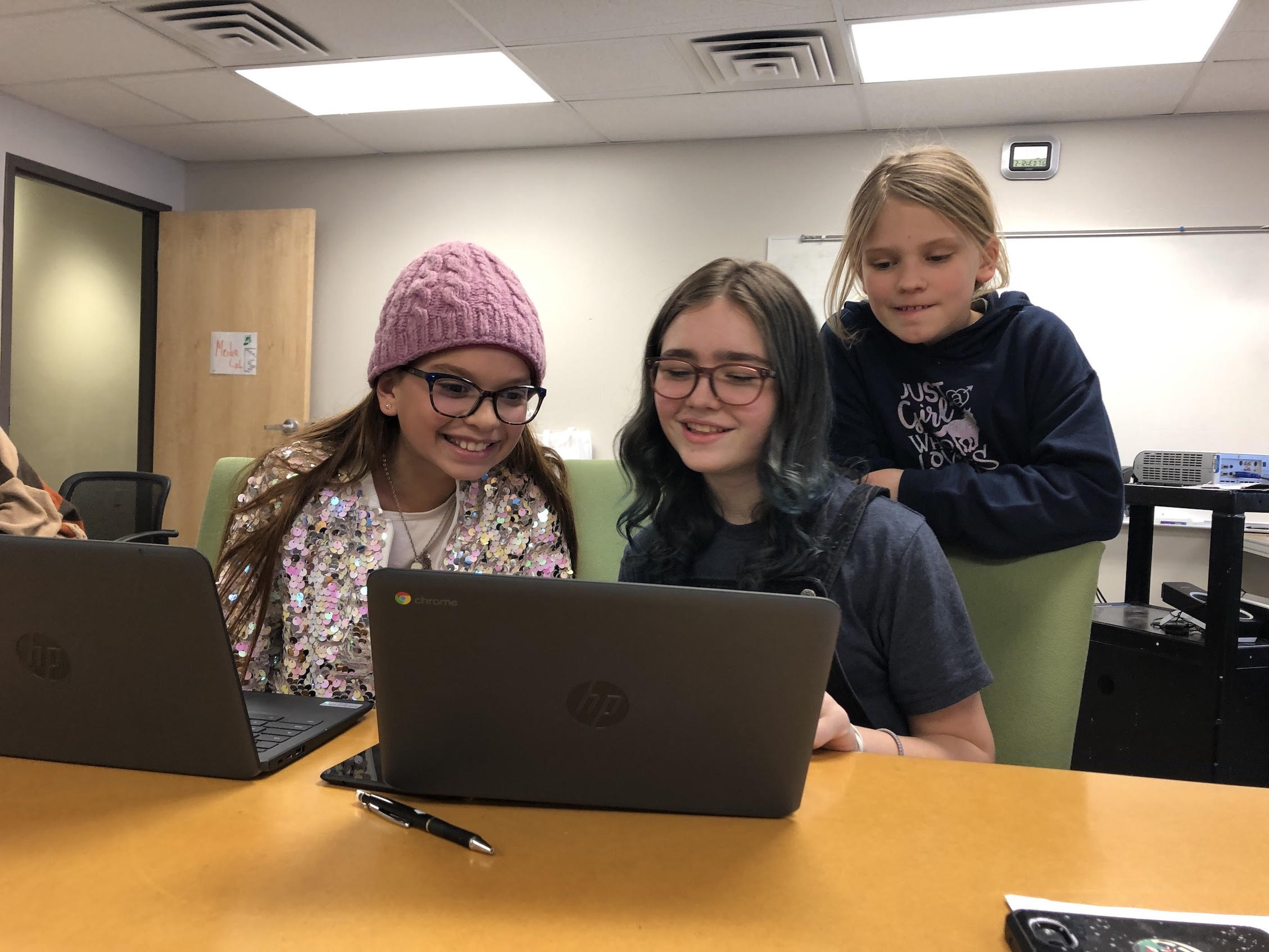 Three young girls work on their Technovation Girls project in front of a laptop